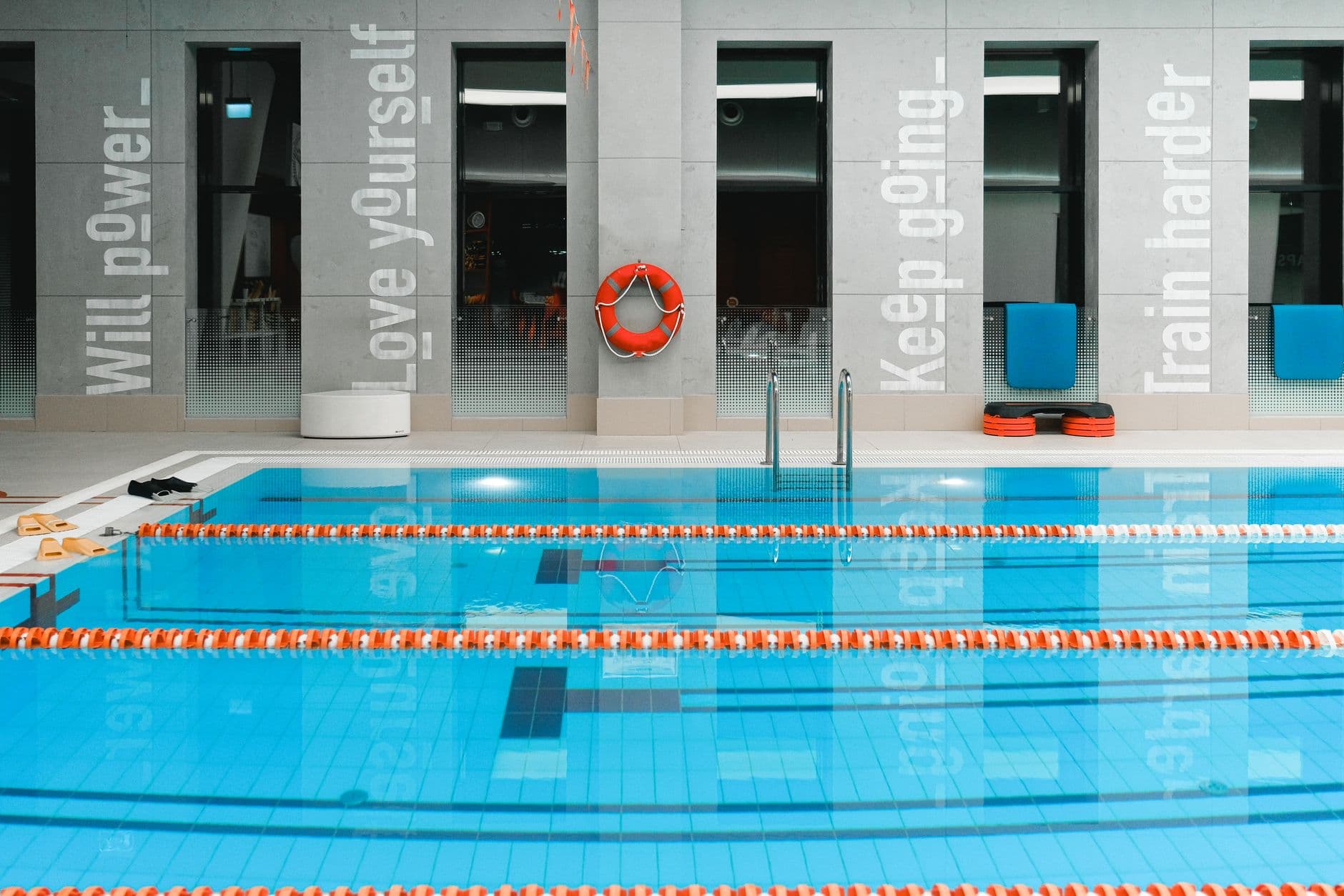 Empty indoor swimming pool divided into lanes by lane ropes